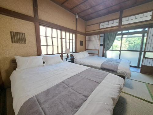 two large beds in a room with windows at 不入斗-横須賀の大型一棟貸し-最大25人-家族団体向け in Yokosuka