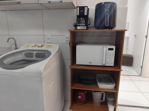 a kitchen with a washing machine and a microwave at Ap à 600 metros da praia, um verdadeiro paraíso! in Barra dos Coqueiros