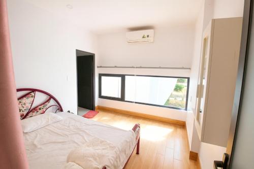 a bedroom with a bed and a large window at Happy Garden Hồ Tràm in Ho Tram