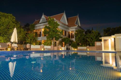 a swimming pool in front of a house at night at La maison bleue BTB in Phumĭ Kâmpóng Âmpĭl