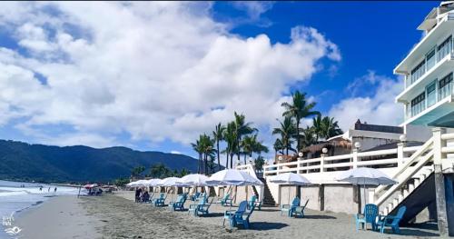 a beach with chairs and umbrellas and a building at Bay's Inn Resort in Baler