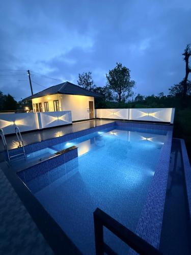 una piscina por la noche con una casa en el fondo en Kenza Retreat, en Vagamon
