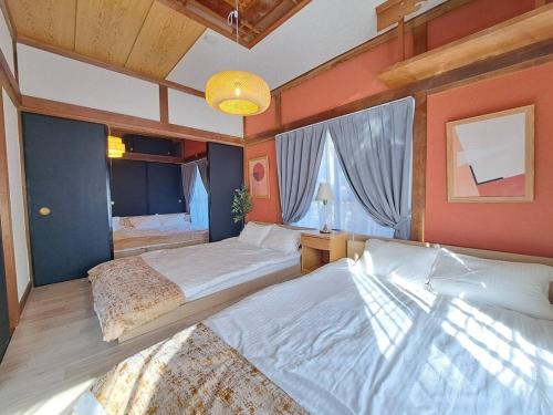 a bedroom with two beds and a large window at 西逸見 in Yokosuka