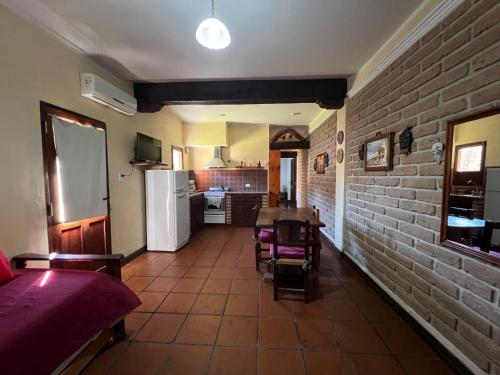 Departamento Cafayate في كفايات: مطبخ وغرفة طعام مع طاولة وجدار من الطوب