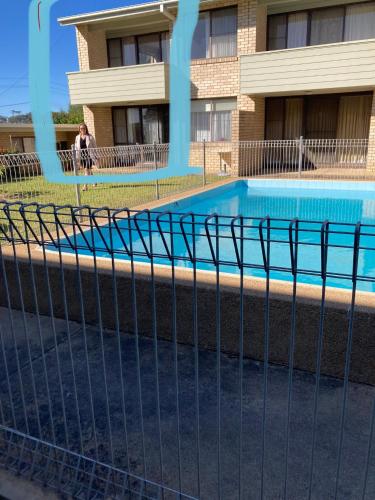 a fence with a swimming pool in front of a building at Beach front apartment in Batemans Bay