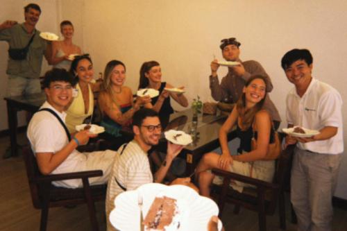 a group of people sitting around a table eating cake at Sanga Rooftop Hostel in Pakse