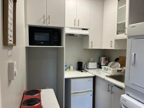 una piccola cucina con armadietti bianchi e forno a microonde di Surrey Home - King George Blvd & Rapid Transit - Airport 25 Min - Free Parking & Wi-Fi a Surrey