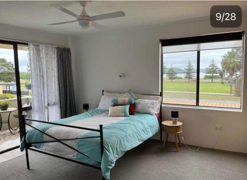a bedroom with a bed and a large window at Beach front apartment in Batemans Bay