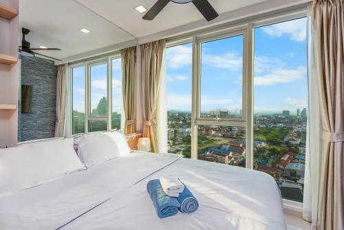 a bedroom with a white bed with large windows at Rare Panoramic Sea, City & Mountain Views - XXL Balcony - 1Gbps Blazing Fast Free WIFI - Pool - Gym - Pool Table - Steam - Sauna - Bar in Pattaya South
