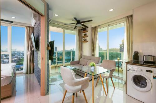 a living room with a glass table and chairs at Rare Panoramic Sea, City & Mountain Views - XXL Balcony - 1Gbps Blazing Fast Free WIFI - Pool - Gym - Pool Table - Steam - Sauna - Bar in Pattaya South
