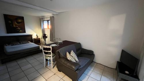 a living room with a couch and a table and a bed at Beach Studio - 24h24 et 7j7 in Petite Île