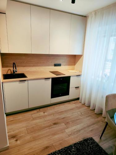 a kitchen with white cabinets and a sink at Apartamentai šalia miesto centro in Telšiai