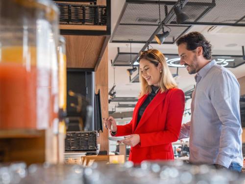 瓜拉普阿瓦ibis Guarapuava的站在柜台后面的男人和女人