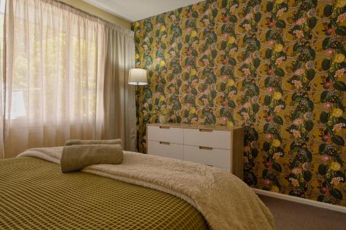 a bedroom with a bed and a wall covered in wallpaper at Cotswold Retreat in Christchurch