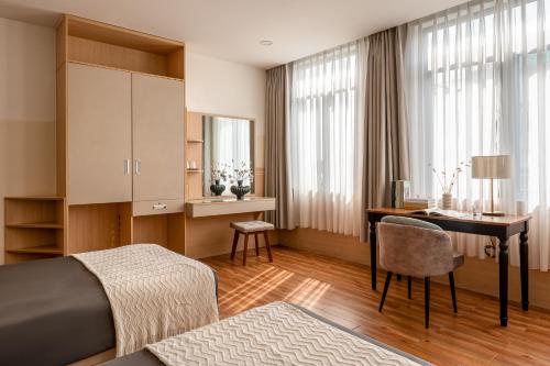 a hotel room with a desk and a bedroom at Tago Airport Hotel in Ho Chi Minh City