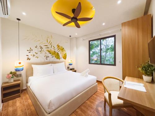 Schlafzimmer mit einem Bett, einem Schreibtisch und einem Deckenventilator in der Unterkunft Sujet Center Hotel by Haviland in Đà Nẵng