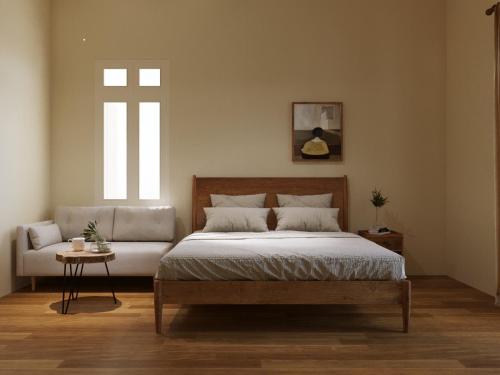 a bedroom with a bed and a couch and a window at Indochine Gloria Home by Silk Path in Hanoi