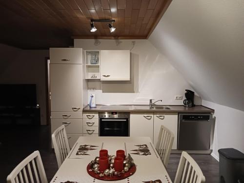a kitchen with a table and chairs and a kitchen with white cabinets at Seeblick- Noer in Noer