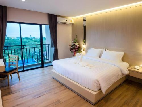 a bedroom with a large white bed and a balcony at L Hotel in Ban Si Than