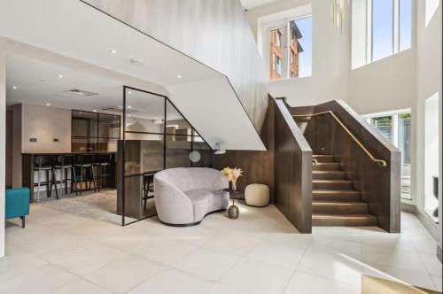 a living room with a staircase and a white couch at Deluxe 2BR Flat with Cinema, Gym, Parking & Games in New Malden