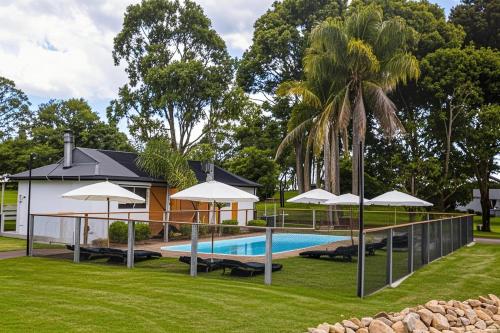 a house with a swimming pool with umbrellas at Eight Acres Lakes Entrance in Lakes Entrance