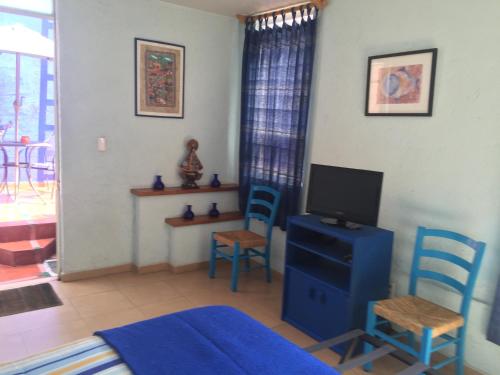 a living room with a tv and two blue chairs at Maria Del Alma House in Mexico City