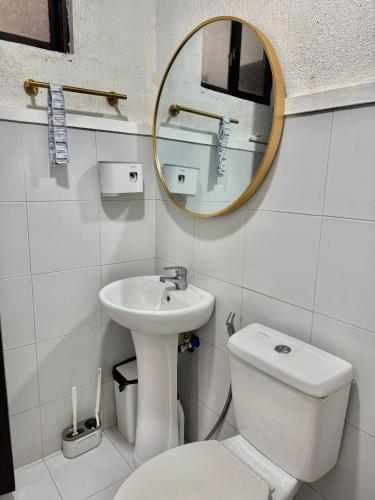 a bathroom with a sink and a toilet and a mirror at Sofias Townhouse for Rent in Dasmariñas