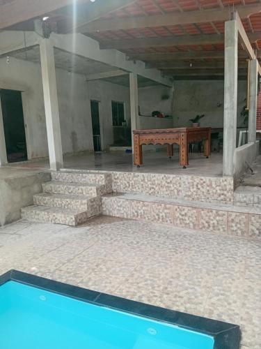 a pool in a room with a table and stairs at Chácara silva in Nova Serrana