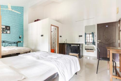 een slaapkamer met een wit bed en een blauwe muur bij Casa De Mor Villa with Pool in Anjuna