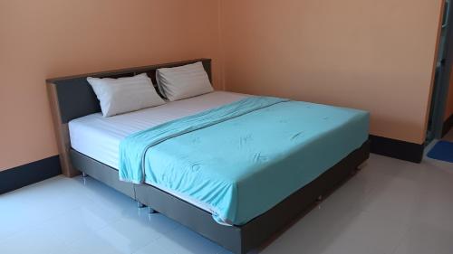 a bed with blue sheets and pillows in a room at สำเภาทองรีสอร์ท in Ban Don Sai