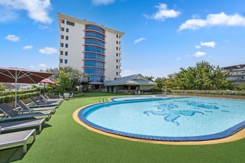a large swimming pool with lounge chairs and a tall building at Town in Town Hotel Bangkok in Bangkok