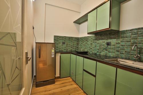 バルカラにあるamaze Beach Resortのキッチン(緑のキャビネット、ステンレス製の冷蔵庫付)