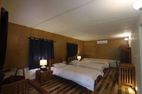 a room with three beds and two tables with lamps at Coffee Courtyard in Kurchi