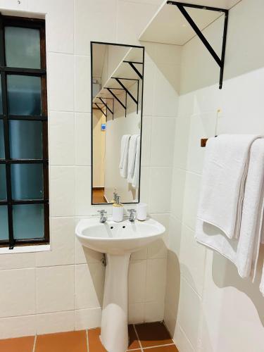 a white bathroom with a sink and a mirror at Alwande's Guesthouse in Richards Bay