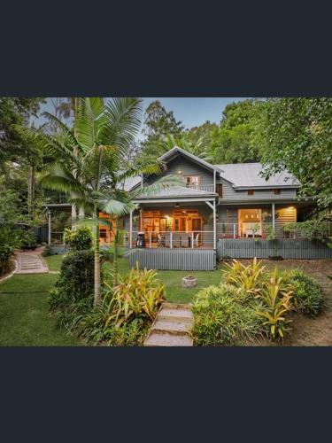a house with a palm tree in front of it at Magnolia Cottage in Cooroy