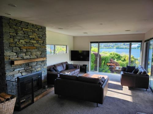 a living room with couches and a stone fireplace at Peninsular Lakefront in Queenstown