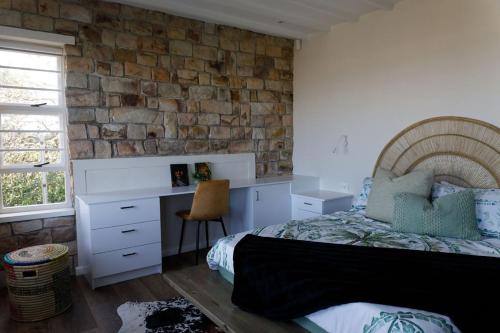 a bedroom with a bed and a brick wall at Fabella Serenety Flat in Muizenberg