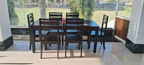 uma mesa de jantar em madeira com cadeiras e uma janela em Takery Resort em Chittaurgarh