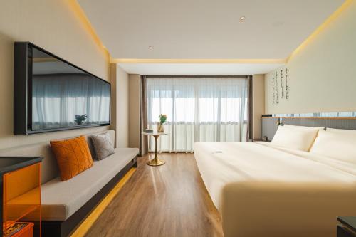 Atour S Hotel Wuxi Nanchang Street في ووشي: غرفة فندقية بها سرير كبير وأريكة