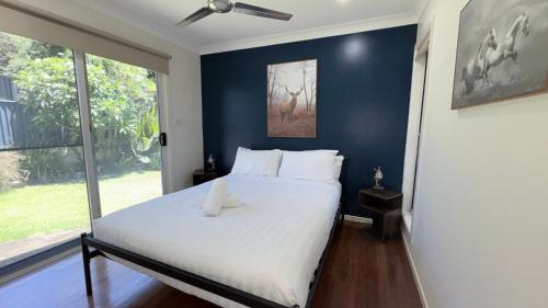 a bedroom with a white bed with a blue wall at Station on Pearce in Coffs Harbour