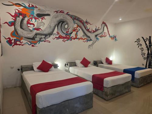 a room with two beds with a dragon on the wall at Dream Hotel in Gili Trawangan