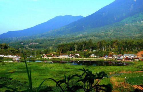 a village with a river and mountains in the background at Elle Maya Sari in Kotabaru