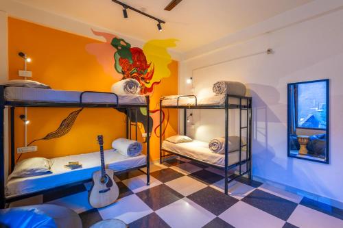 a room with three bunk beds and a guitar at Himtrek Stays Katagala in Kasol