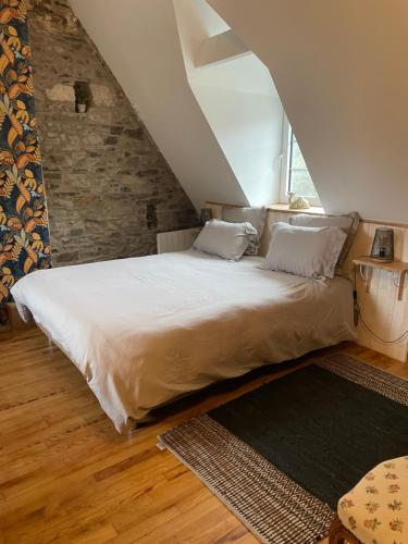 a bedroom with a large bed in a attic at Moulin entier rénové in Plounéventer