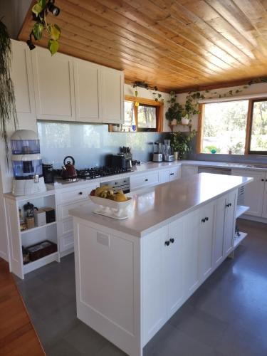 a white kitchen with a bowl of fruit on a counter at Queen Room with Balcony - Kookaburra Retreat Homestay in Pakenham