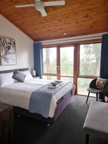 a bedroom with a large bed and a large window at Queen Room with Balcony - Kookaburra Retreat Homestay in Pakenham