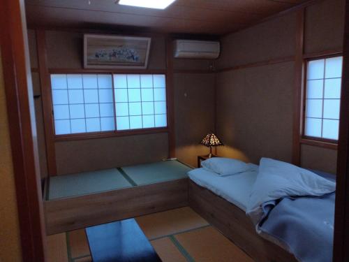 a small bedroom with a bed and two windows at Kyoto Narutaki Keisenso in Kyoto