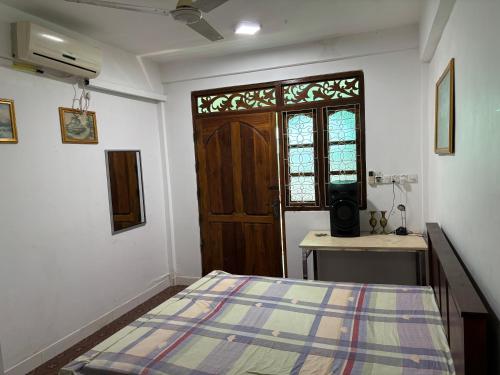 Un dormitorio con una cama y una puerta de madera. en Sj Hotel Jaffna, en Jaffna