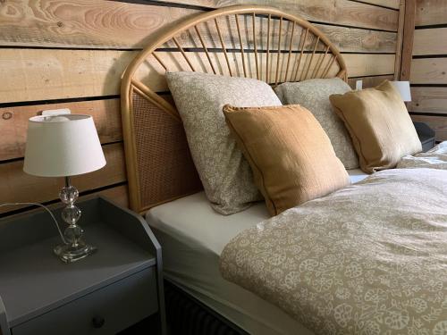 a bed with pillows and a lamp on a table at Le printemps, gîte nature in Bruyères