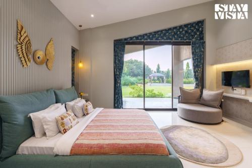 a bedroom with a large bed with a couch and a window at StayVista at Villa Lemonade with BBQ & Bonfire in Alibaug